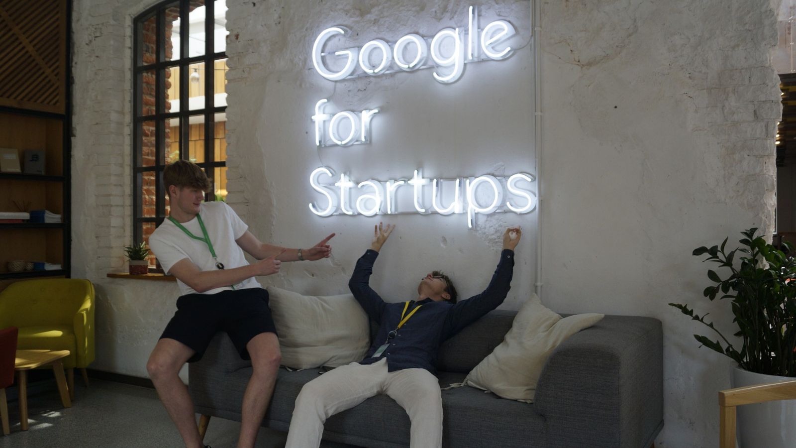 Mikita lying back on a sofa under a Google for Startups neon sign while a teammate points at him.