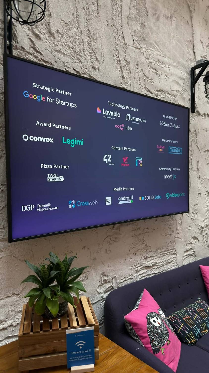 A screen on a stone wall listing the hackathon partners: Google for Startups as strategic partner, Lovable, JetBrains and n8n as technology partners, Convex and Legimi as award partners, and media and community partners.