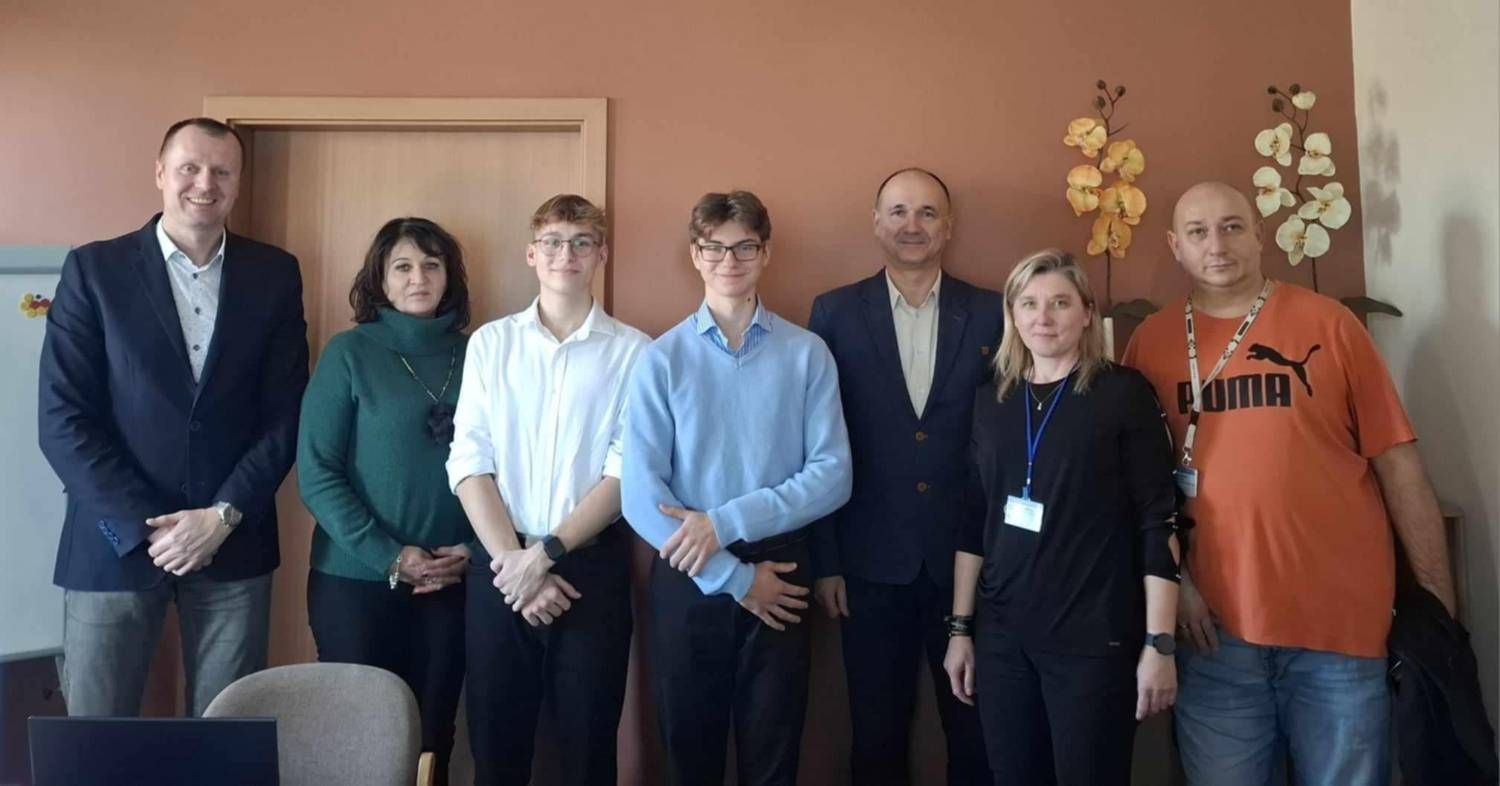 Group photo of Mikita and Mikołaj with county officials and hospital staff in an office.