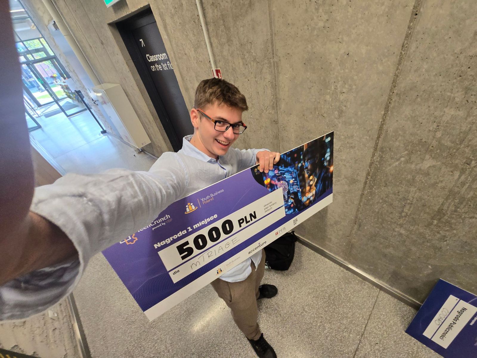 Selfie of Mikita holding a large TeenCrunch cheque for first place, 5,000 PLN, made out to mTriage.