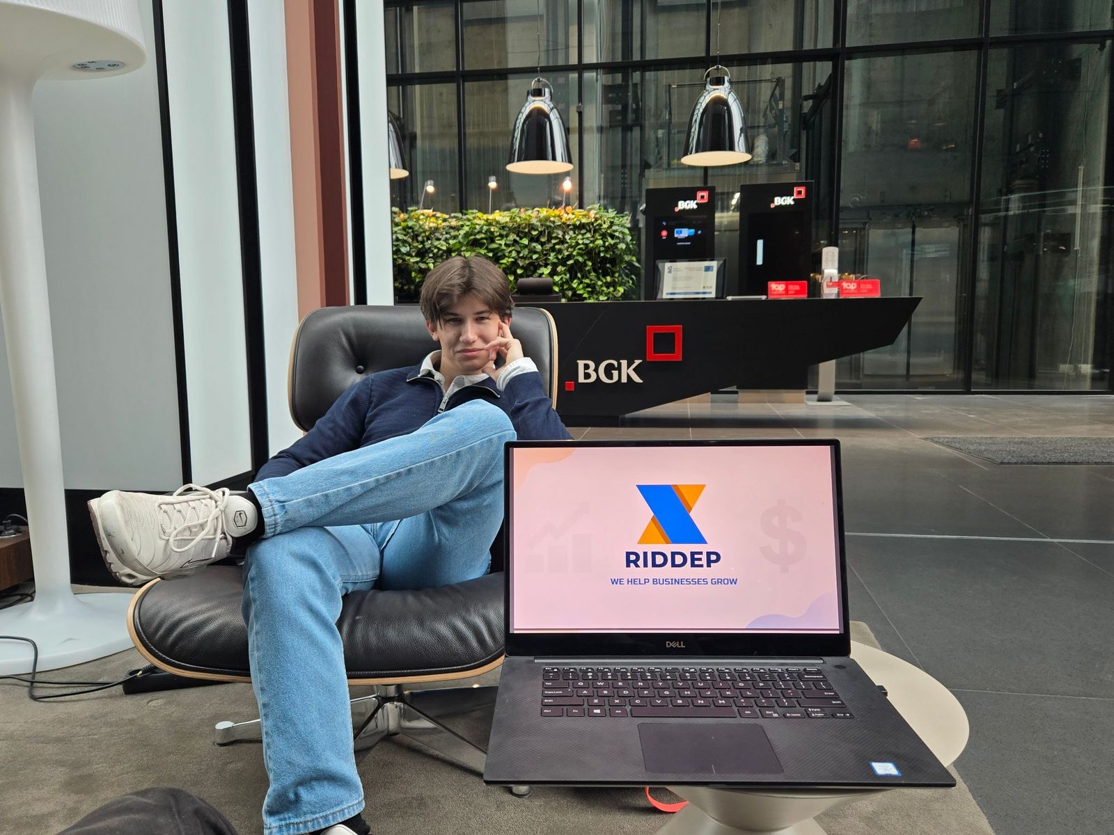 Radosław Soysal sitting in a lounge chair next to a laptop showing the Riddep title slide.