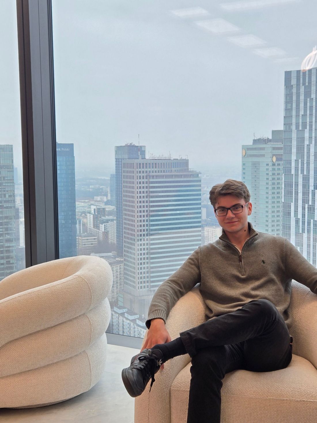 Mikita sitting in an armchair by a window high above central Warsaw.